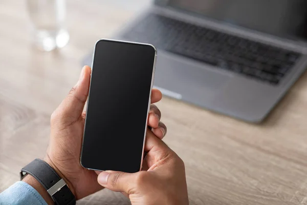 Homme d'affaires afro-américain millénaire méconnaissable tenant smartphone avec écran blanc sur le lieu de travail — Photo