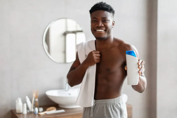 목욕 방에서 샤우어 젤 병을 보여 주는 쾌활 한 아프리카 계 미국인 남자 — 스톡 사진