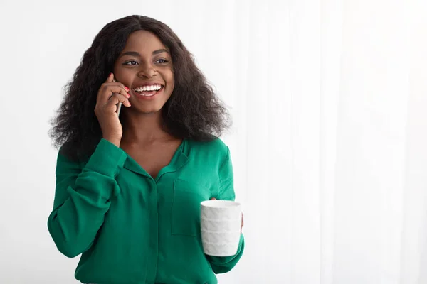 Wanita kulit hitam yang bahagia menikmati kopi di pagi hari, mengobrol di telepon — Stok Foto