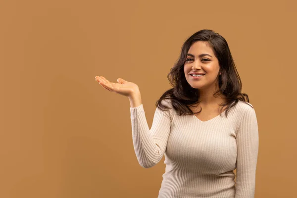 Check this offer. Positive arab lady holding her open palm, demonstrating invisible object, beige background, free space — Stockfoto