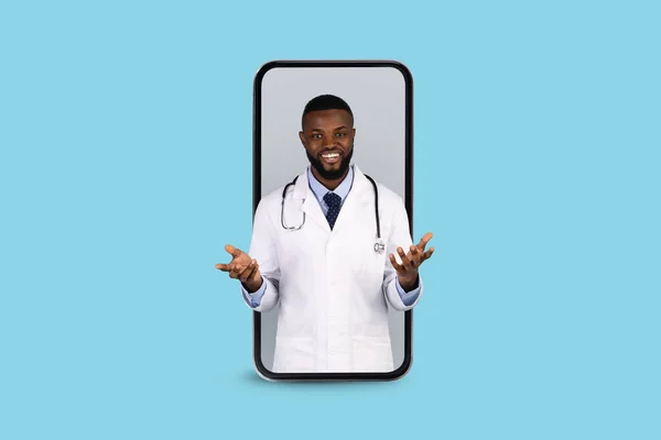 Online Medicine. Smiling Black Doctor Peeking Out Of Big Smartphone Screen — Stock fotografie