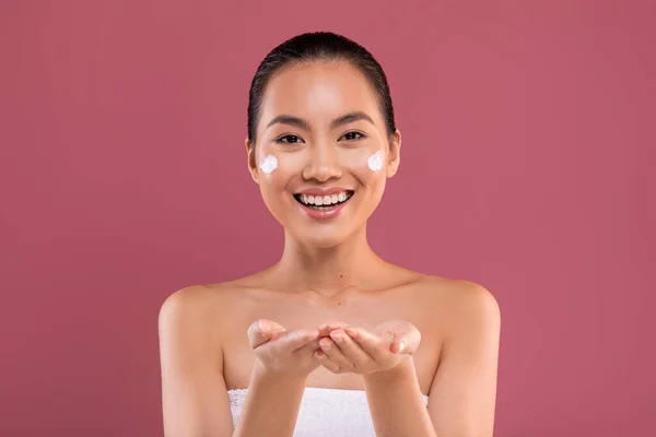 Cheerful asian woman holding something invisible on her hands — Stockfoto