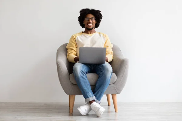 Smiling African American Guy Sitting In Chair With Laptop On Laps — Fotografia de Stock