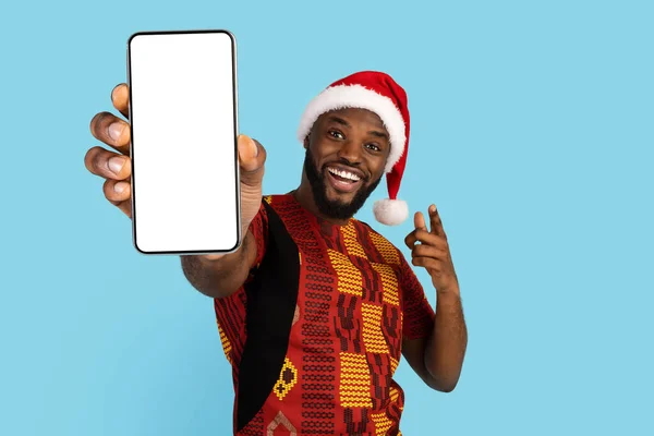 Emocionado hombre negro en traje tradicional y sombrero de Santa Mostrando Smartphone en blanco — Foto de Stock