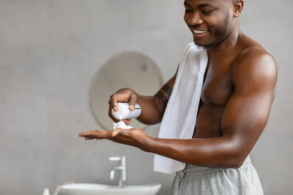 アフリカ系アメリカ人の男が浴室で恥知らずに立つシェービングフォームを適用する — ストック写真