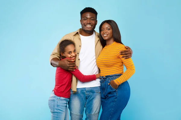 Happy black guy posing with wife and smiling teen daughter