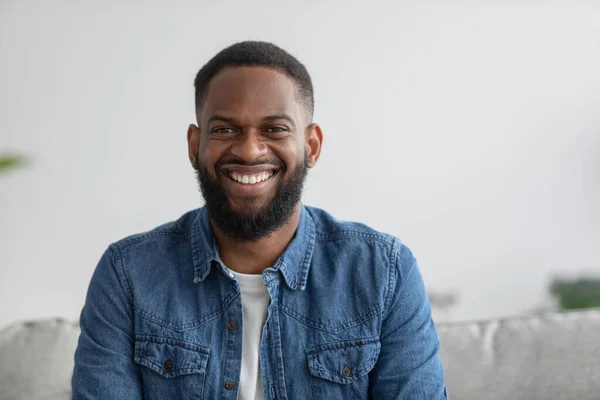 Portrait of cheerful young attractive african american male with beard look at camera in room interior — Stock Fotó