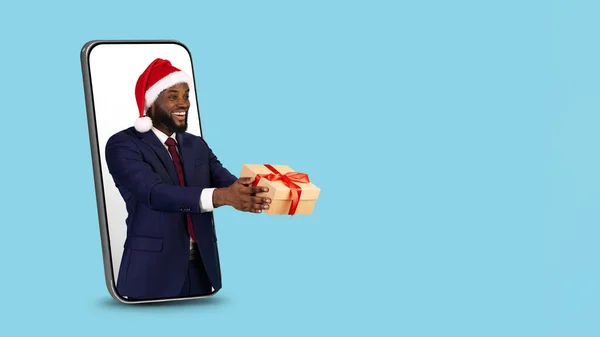 Black Businessman In Santa Hat With Gift Peeking Out Of Big Smartphone — 图库照片