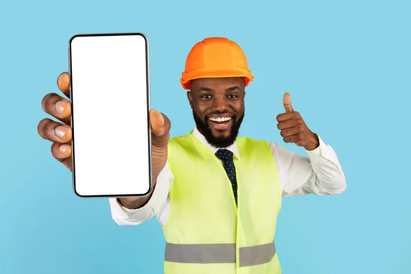 Κατασκευαστικές Υπηρεσίες. Μαύρος εργάτης κατασκευών που επιδεικνύει το κενό Smartphone και επιδεικνύει το αντίχειρα επάνω — Φωτογραφία Αρχείου