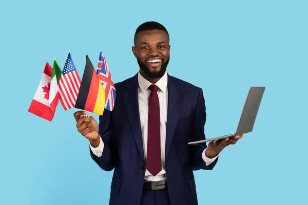 Business Language Courses. Black Businessman Holding Bunch Of Flags And Laptop — Stockfoto