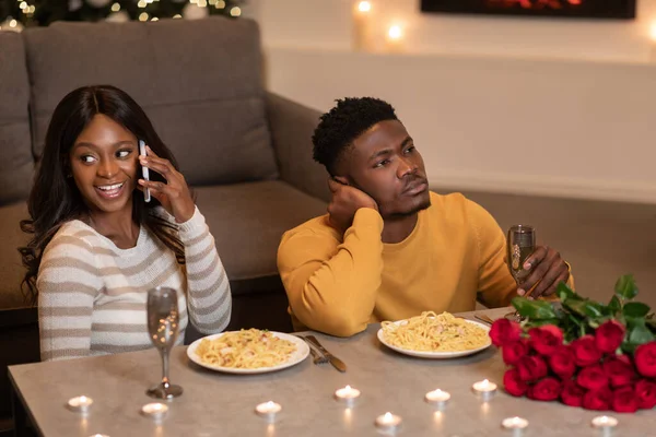 バレンタインディナーの間に黒人男性待っている女性の携帯電話屋内 — ストック写真