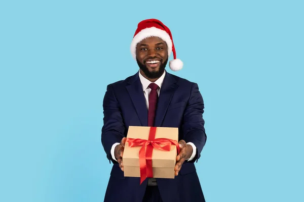 Excited Black Businessman Wearing Santa Hat Giving Gift Box At Camera — Foto de Stock