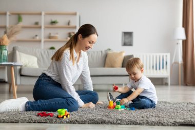 Bebek gelişimi aktiviteleri. Genç ve mutlu anne, sevimli küçük oğluyla evde eğitim oyunları oynuyor.