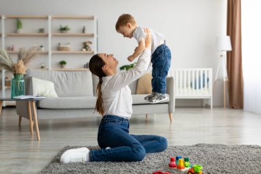 Koşulsuz sevgi. Mutlu anne küçük oğluyla eğleniyor, onu havaya kaldırıyor, evde çocukla oynuyor.