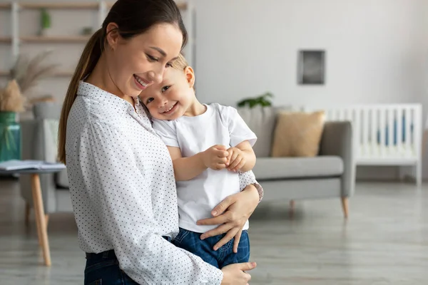 Happy young mom embracing leaning to chest toddler son, spending time together at home, copy space — Foto de Stock