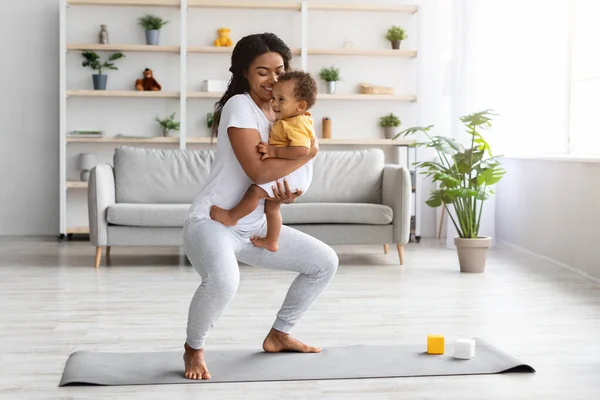 Postpartum Weight Loss. Happy Black Lady Making Squats With Baby On Hands —  Fotos de Stock