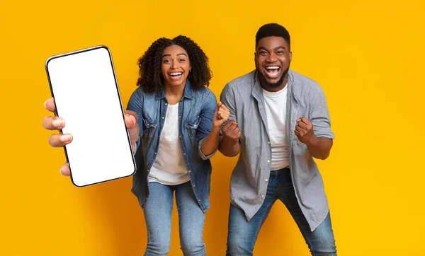 Black couple showing white empty smartphone screen and gesturing yes — Stockfoto