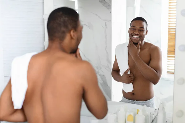 Buenos días Rutina. guapo sin camisa negro chico buscando en espejo y tocando barba — Foto de Stock