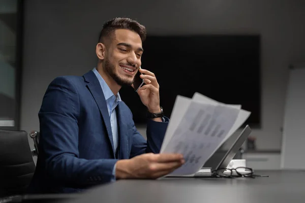 Happy arab CEO reading documents and having phone conversation — Stockfoto