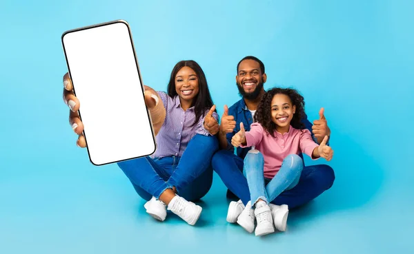 Μαύρη οικογένεια που δείχνει άδεια οθόνη smartphone και τους αντίχειρες επάνω — Φωτογραφία Αρχείου