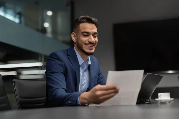 Glimlachende Arabische zakenman checkt rapporten in modern kantoor — Stockfoto