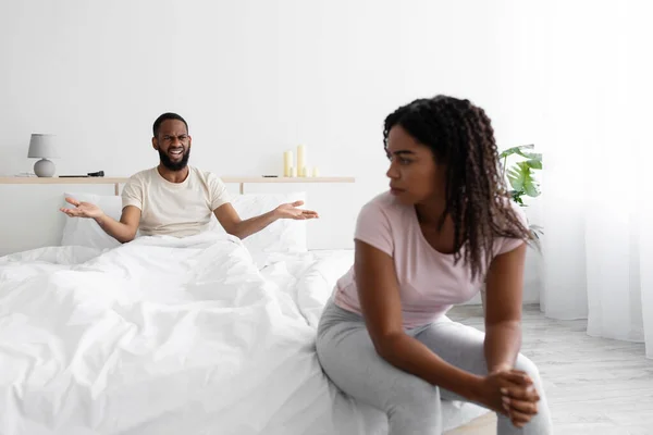 Unhappy angry young black husband freaking out and yells at sad wife, sit on bed — Foto Stock