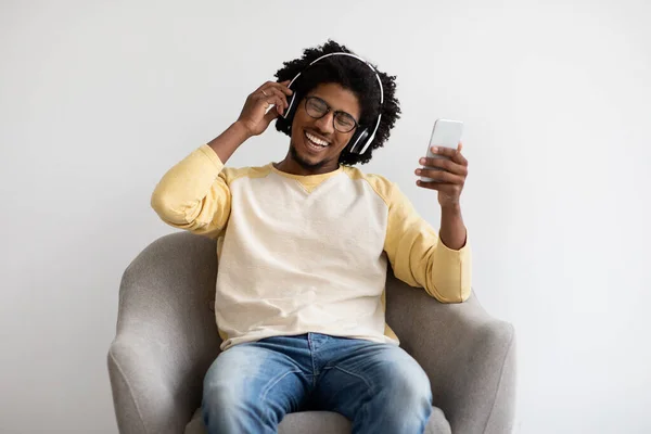 Young Black Guy With Smartphone And Wireless Headphones Relaxing In Armchair — Stock Fotó