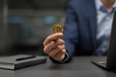 Tanınmayan takım elbiseli işadamı bitcoin gösteriyor, dizüstü bilgisayarla çalışıyor.