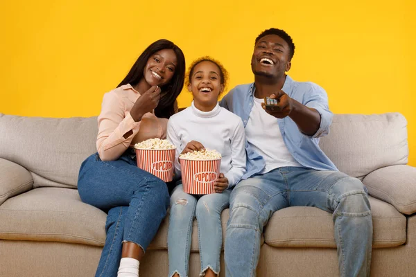 Happy young family watching television sitting on sofa