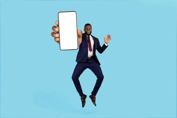 Gek aanbod. Opgewonden zwarte zakenman springen met lege smartphone in de hand — Stockfoto