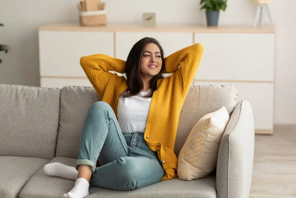 Stay at home alone and enjoy silence. Serene happy arab lady resting on sofa in minimalist living room — Foto Stock