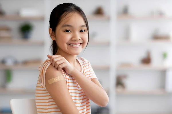 Healthy asian girl got vaccinated, showing band and smiling — Photo