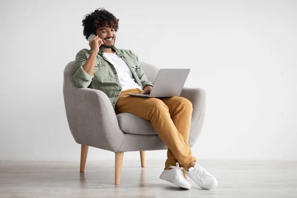 Handsome indian guy working online, having phone conversation — Foto Stock