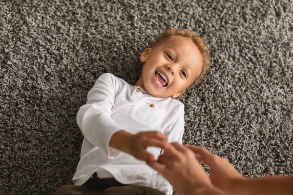 Noir petit garçon rire mensonge tandis que maman chatouiller il intérieur — Photo