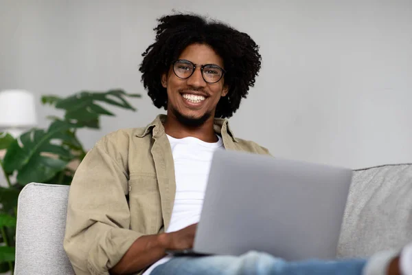 Freelance Work. Smiling Young Black Guy In Eyeglasses Using Laptop At Home — Fotografia de Stock