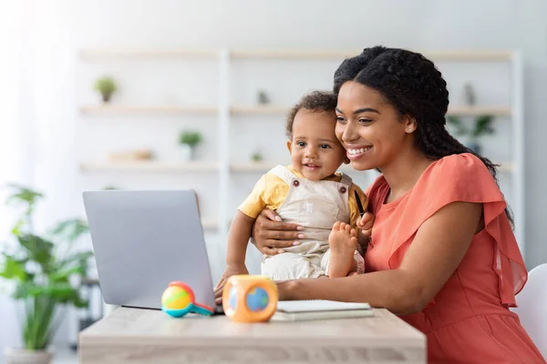 Black Woman Study With Laptop At Home And Taking Care About Child — стоковое фото