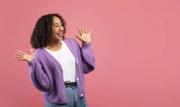 Emotional young black woman shouting in excitement, holding hands near face, looking at empty space over pink background — Fotografia de Stock