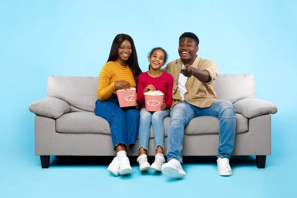 Gelukkig jong gezin kijken televisie met popcorn zitten op de bank — Stockfoto