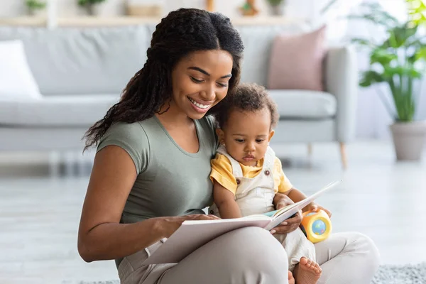 Zorgvuldige Afro-Amerikaanse mama lezen boek voor haar peuter zoon thuis — Stockfoto