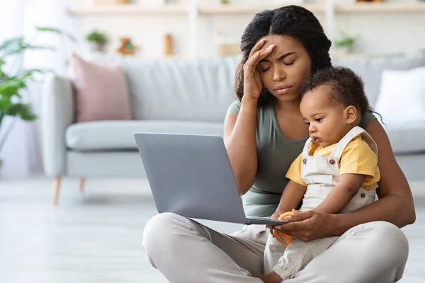 Tired Black Mother Having Problems With Remote Work While Babysitting Toddler Child — стоковое фото