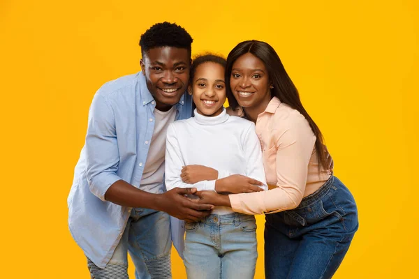 Afro-Amerikaanse man en vrouw knuffelen hun lachende dochter — Stockfoto