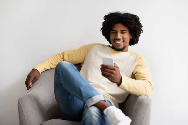 Nice App. Cheerful Black Millennial Guy Relaxing In Chair With Smartphone — Stock Fotó