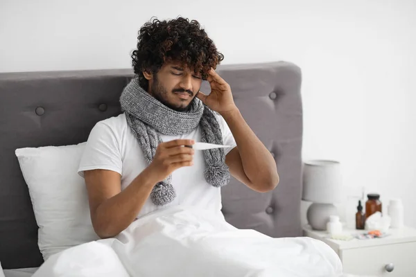 Ill indian guy with scarf around neck checking temperature — Stock Fotó