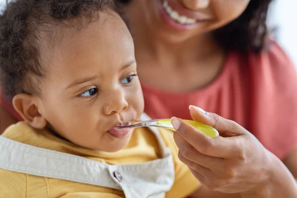 Baby Feeding. Closeup Of Cute Little Black Infant Boy Eating From Spoon — стоковое фото