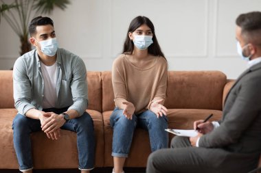 Terapi seansında erkek terapistle konuşan maskeli bir çift.