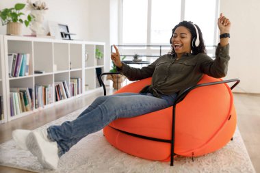 Zenci kadın kulaklıkla müzik dinliyor ve dans ediyor.