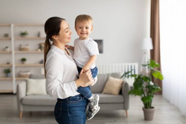 Mothers love. Young mom holding toddler son on hands, little kid looking at camera and smiling, free space