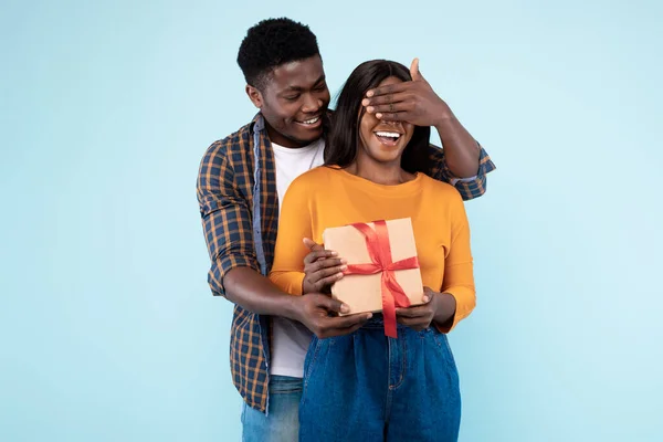Happy black man making surprise for his woman giving box — Stockfoto