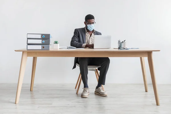 Young black businessman working from home office with laptop, wearing face mask during coronavirus quarantine — Fotografia de Stock