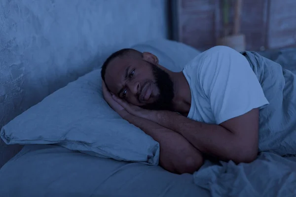 Black man lying in bed and thinking in the night — Stockfoto